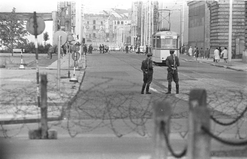 Bewaffnete Angehörige der DDR-Einheiten stehen im August 1961 an einer provisorisch abgesperrten Berliner Straße.